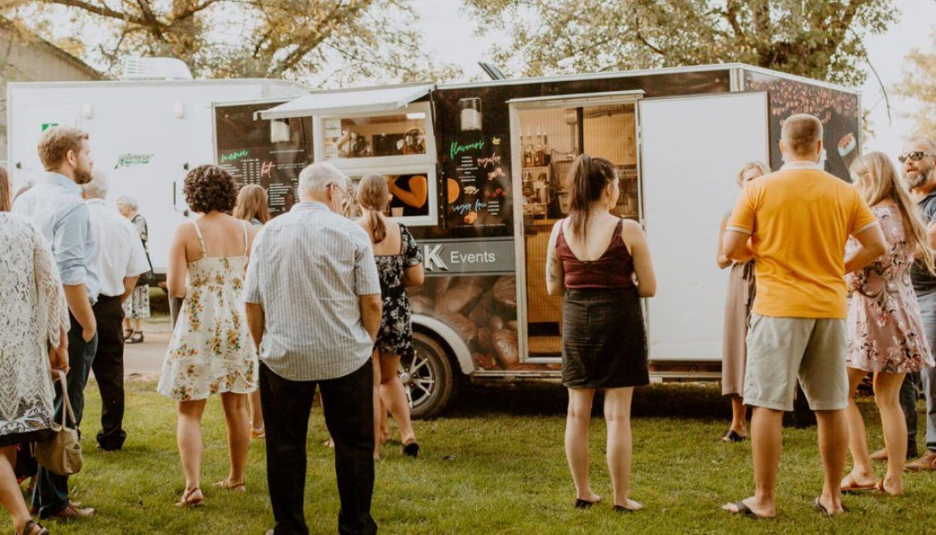 Guests queueing at a coffee trailer outdoors